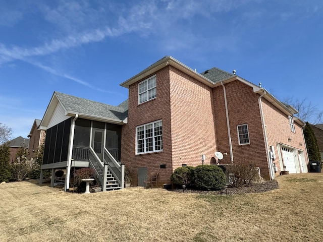 view of side of home with roof with shingles, a sunroom, a garage, a lawn, and brick siding