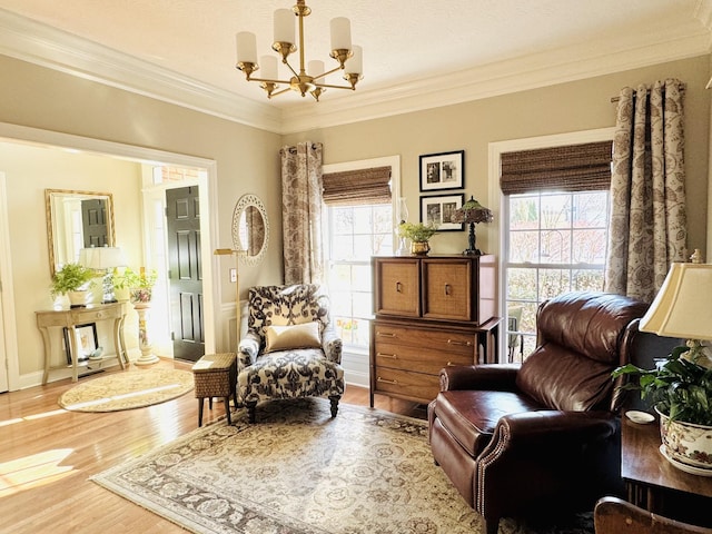 sitting room with wood finished floors, plenty of natural light, a chandelier, and crown molding