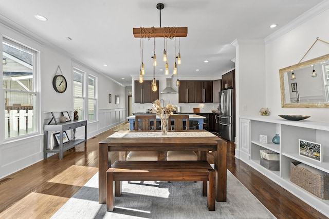 dining room featuring a wainscoted wall, wood finished floors, crown molding, a decorative wall, and recessed lighting