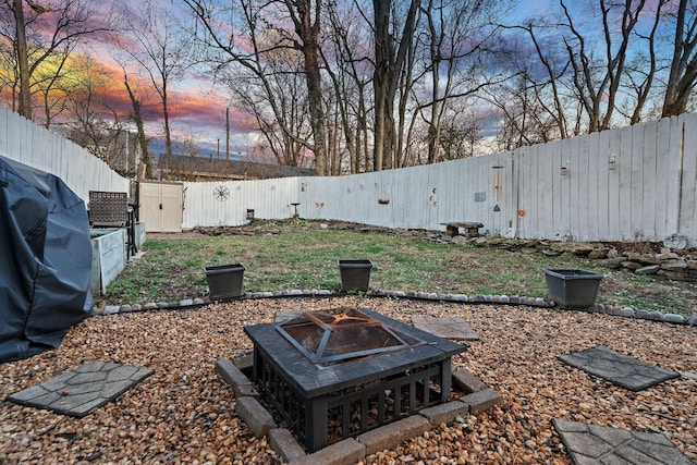 yard at dusk featuring a fenced backyard and a fire pit