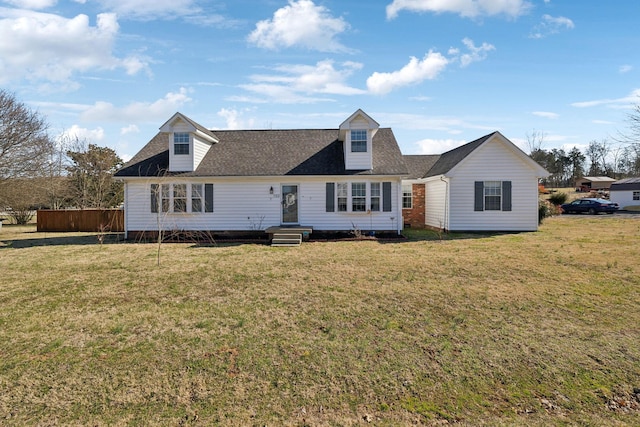 new england style home featuring a shingled roof, fence, and a front lawn