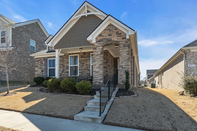 craftsman-style house featuring central AC and stone siding