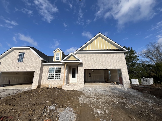 view of front of property featuring a garage, driveway, brick siding, and board and batten siding