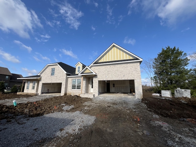 view of front facade featuring a garage, brick siding, and board and batten siding