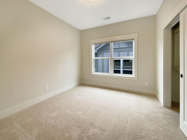 spare room with light colored carpet, visible vents, and baseboards