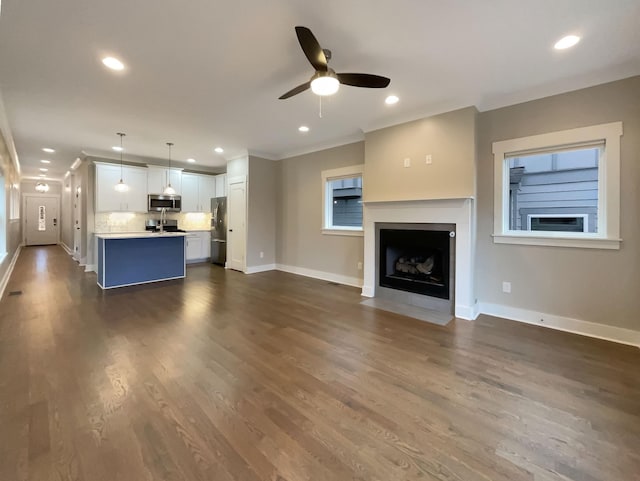 unfurnished living room featuring baseboards, ornamental molding, and recessed lighting