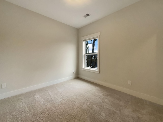 spare room with baseboards, visible vents, and light colored carpet