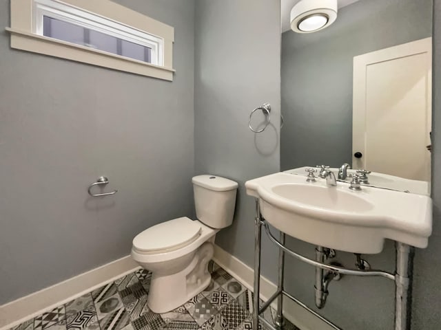 bathroom with tile patterned flooring, baseboards, and toilet