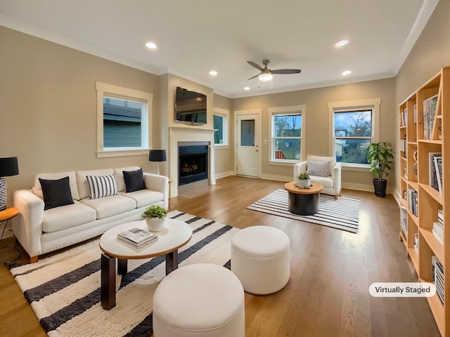 living room featuring recessed lighting, crown molding, wood finished floors, and a fireplace with flush hearth