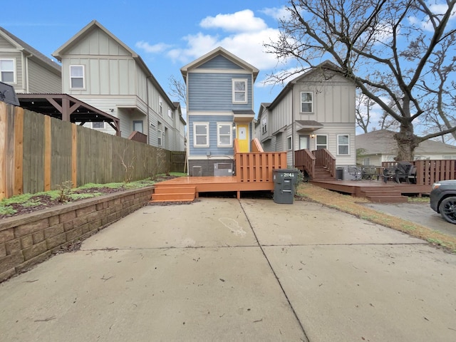 back of house with board and batten siding, a patio area, fence, and a wooden deck