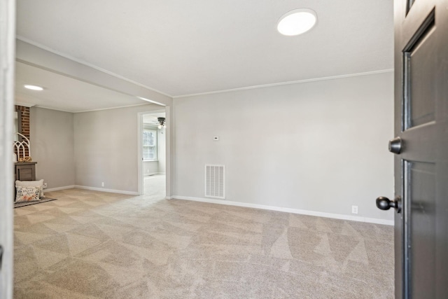 spare room with carpet floors, ornamental molding, visible vents, and baseboards