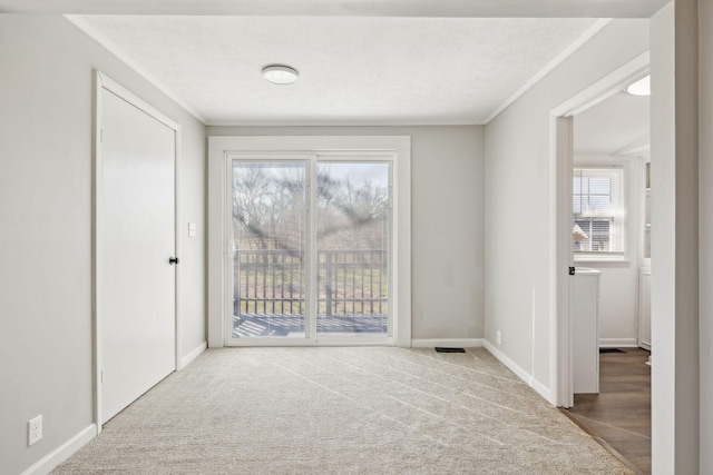 carpeted empty room featuring crown molding, a textured ceiling, and baseboards