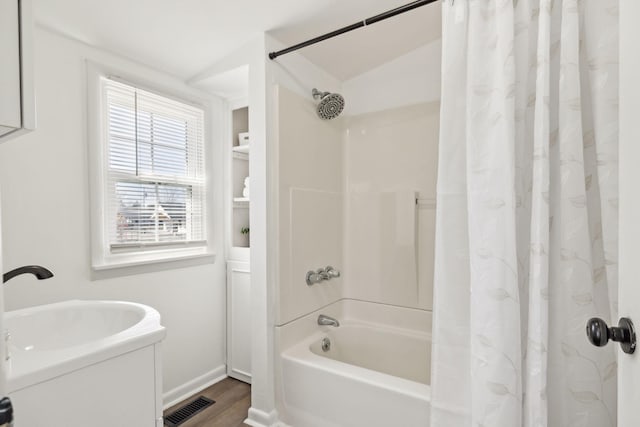 full bathroom featuring shower / bath combo, visible vents, baseboards, and wood finished floors