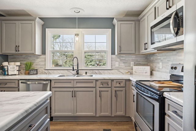 kitchen featuring decorative backsplash, gray cabinets, a textured ceiling, stainless steel appliances, and a sink