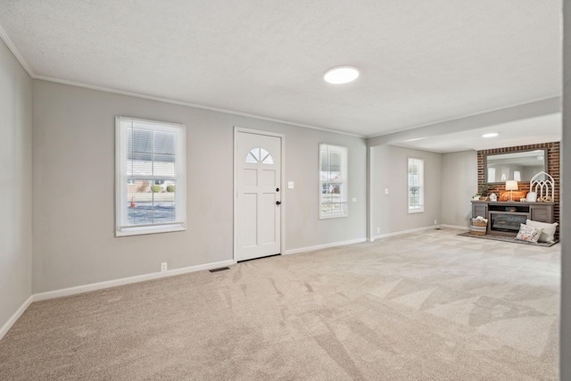 foyer with visible vents, baseboards, ornamental molding, carpet, and a textured ceiling