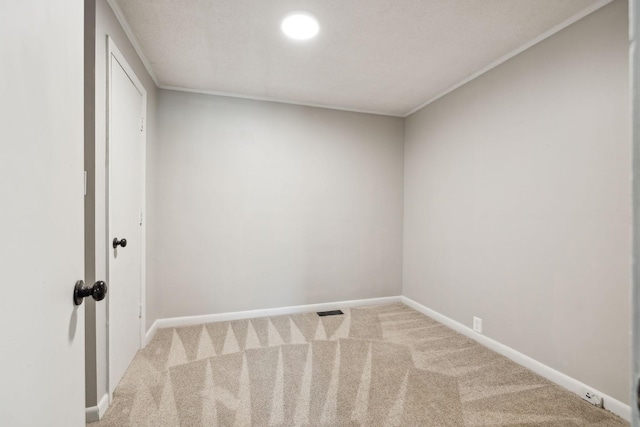 empty room with carpet floors, ornamental molding, visible vents, and baseboards