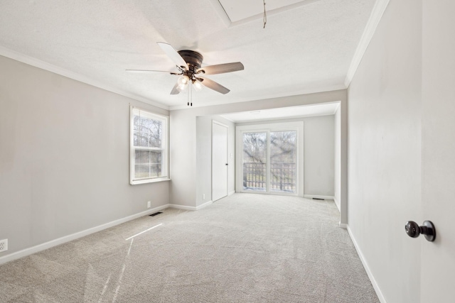 unfurnished room with ornamental molding, carpet, attic access, and baseboards