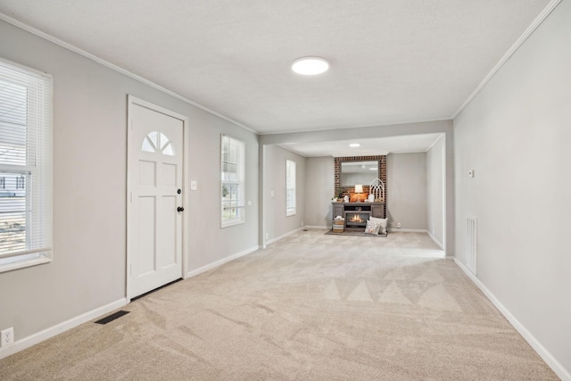 carpeted entrance foyer with a glass covered fireplace, a healthy amount of sunlight, visible vents, and baseboards