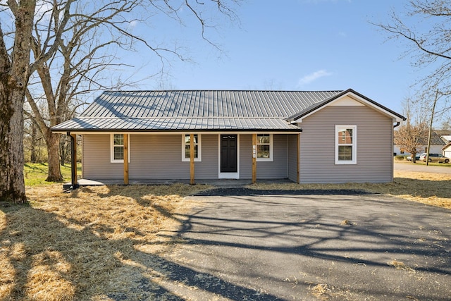 view of front facade featuring driveway, covered porch, and metal roof