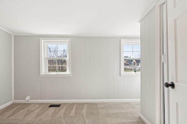 empty room with carpet floors, visible vents, and plenty of natural light