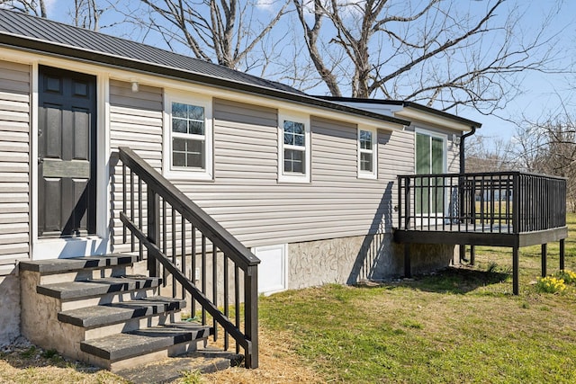 view of exterior entry featuring a deck, metal roof, a standing seam roof, and a lawn