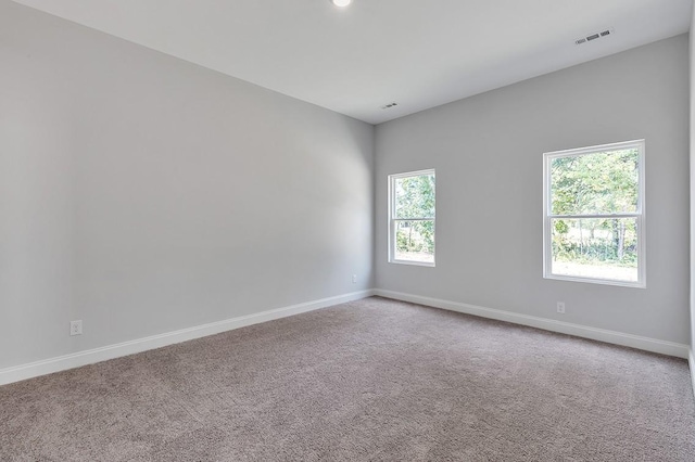 empty room featuring carpet flooring, visible vents, and baseboards