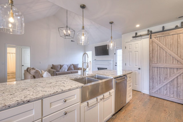 kitchen with light wood-style flooring, a sink, white cabinetry, open floor plan, and stainless steel dishwasher