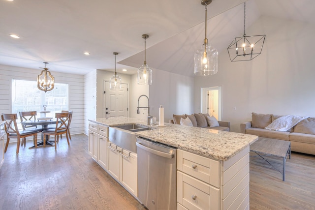 kitchen featuring a sink, open floor plan, stainless steel dishwasher, and wood finished floors