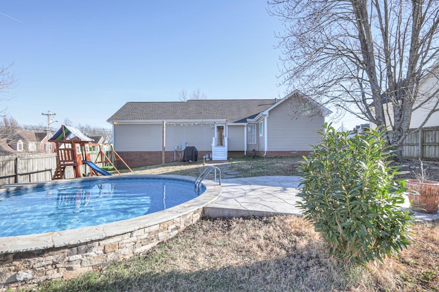 view of swimming pool featuring a patio, a playground, fence, and a fenced in pool