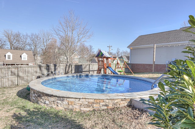 view of swimming pool featuring a playground and a fenced backyard