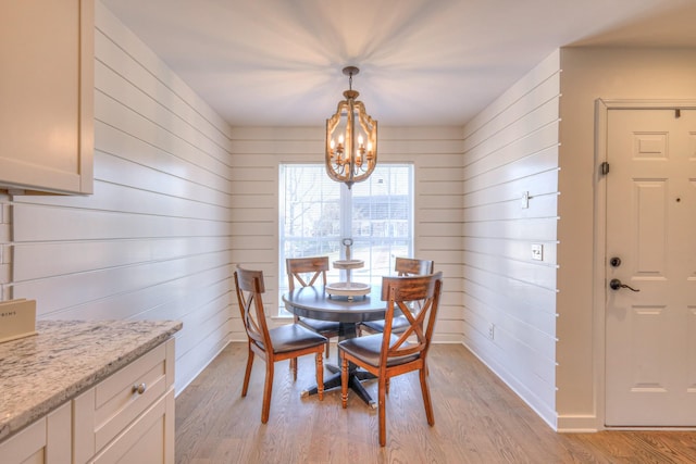 dining space with an inviting chandelier, light wood-style flooring, and baseboards