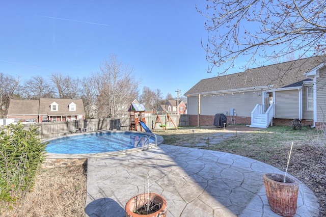 view of swimming pool with a patio, a fenced backyard, a residential view, a grill, and a playground