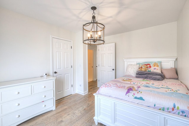 bedroom featuring light wood finished floors and an inviting chandelier