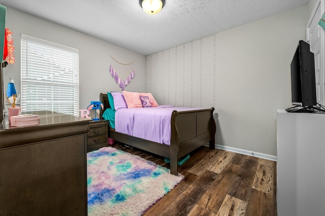 bedroom with a textured ceiling, baseboards, and wood finished floors