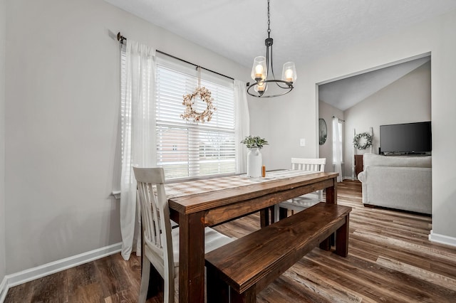 dining space featuring baseboards, vaulted ceiling, an inviting chandelier, and wood finished floors