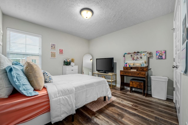 bedroom featuring a textured ceiling, wood finished floors, and baseboards