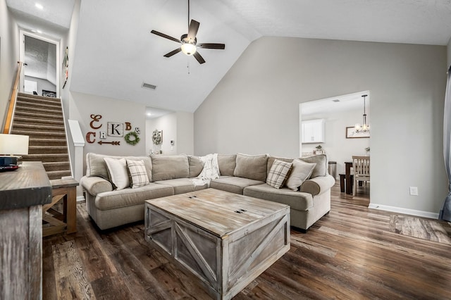 living room featuring dark wood-style floors, stairs, visible vents, and ceiling fan with notable chandelier