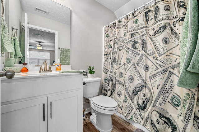 bathroom with a textured ceiling, toilet, wood finished floors, vanity, and visible vents