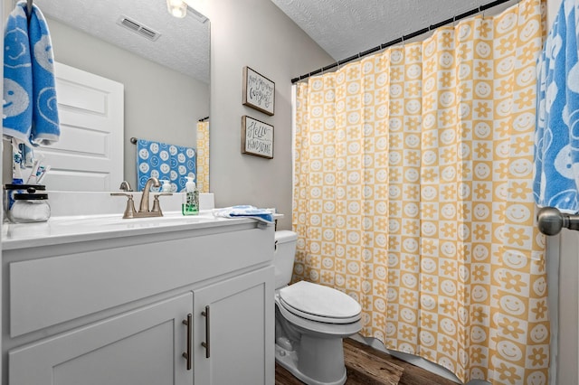 bathroom with visible vents, a textured ceiling, toilet, and wood finished floors