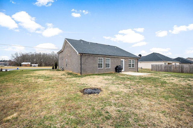 rear view of house featuring brick siding, a patio, a lawn, and fence