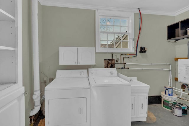 clothes washing area featuring ornamental molding, cabinet space, and washer and dryer