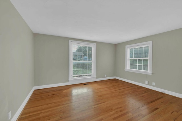 spare room featuring visible vents, baseboards, and wood finished floors