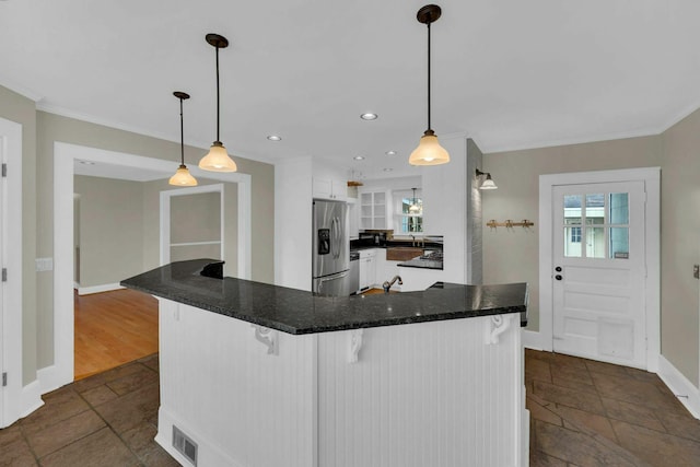 kitchen with stainless steel fridge, baseboards, white cabinets, a kitchen breakfast bar, and crown molding