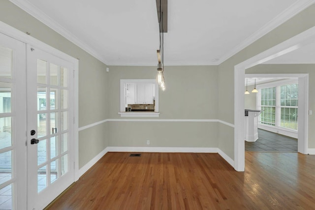 unfurnished dining area with visible vents, baseboards, wood finished floors, crown molding, and french doors