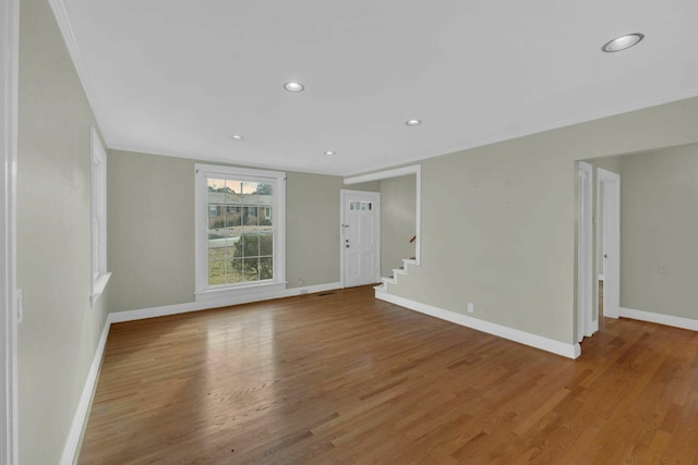 unfurnished room featuring recessed lighting, wood finished floors, baseboards, stairway, and crown molding