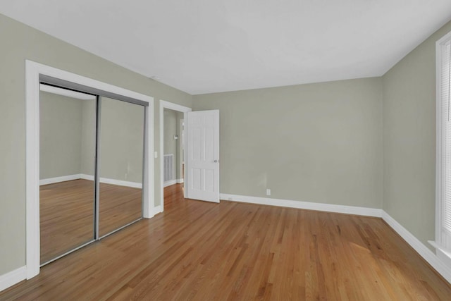 unfurnished bedroom featuring light wood-type flooring, visible vents, baseboards, and a closet