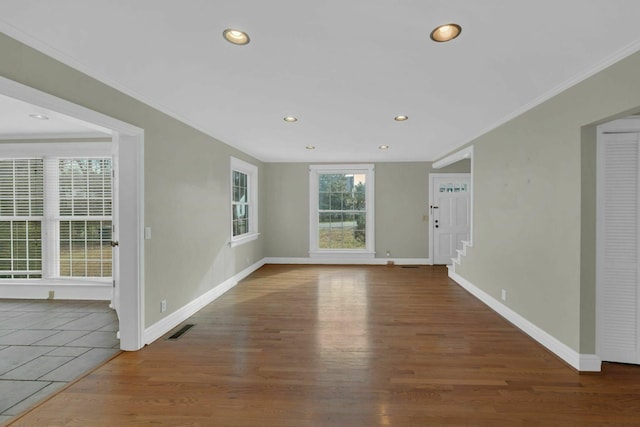 unfurnished room with baseboards, wood finished floors, visible vents, and crown molding