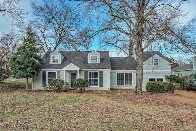 cape cod house featuring brick siding and a front lawn