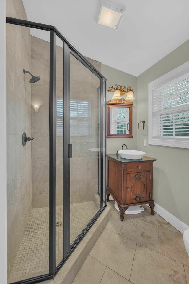 bathroom with a stall shower, vanity, baseboards, and tile patterned floors