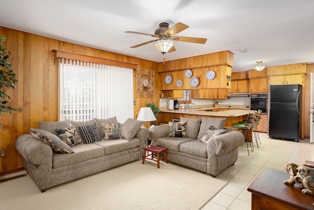 living room featuring light tile patterned floors, wood walls, visible vents, and a ceiling fan